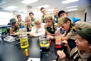 Scouts gather around a beaker of water and oil during a visual lesson in liquid viscosity in the Chemistry Course at Merit Badge University 4. (Photo credit: Lido Vizzutti)